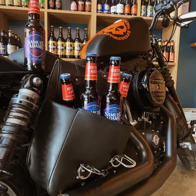 Bouteilles de bière calées dans la sacoche d’une moto exposée dans le bar