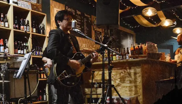 Guitariste en concert entre les étagères de bouteilles