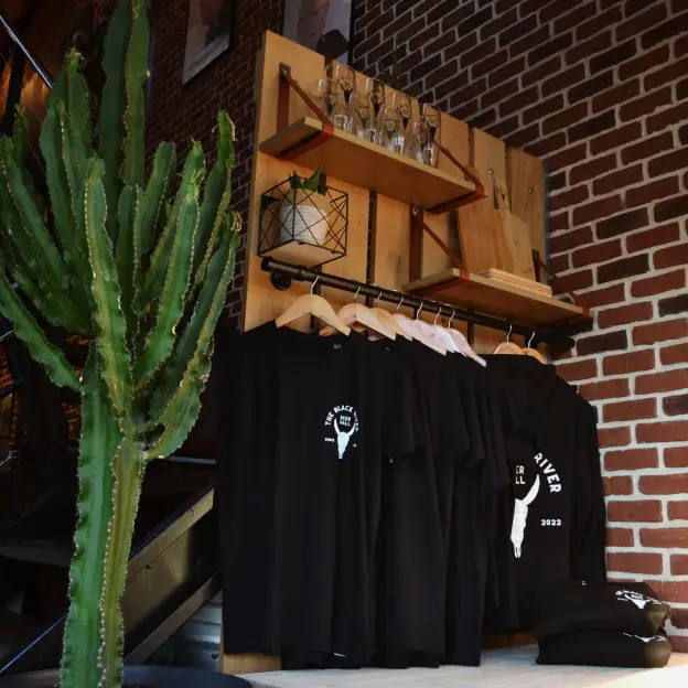 T-shirts noirs The Black River suspendus à côté d’un grand cactus