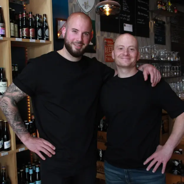 Julien et Cédric, les patrons du Black River, bar à bières à Rambouillet, devant les étagères de bouteilles