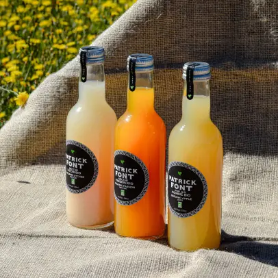 Trois bouteilles de jus Patrick Font dans l’herbe